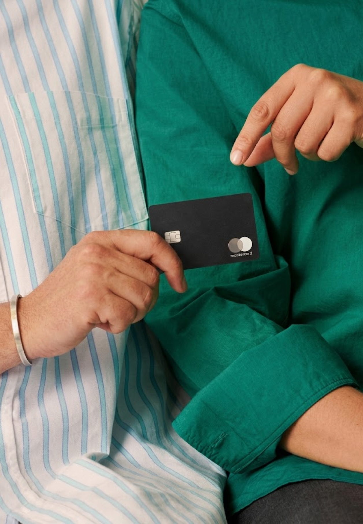 Hand slipping a black payment card into a shirt pocket